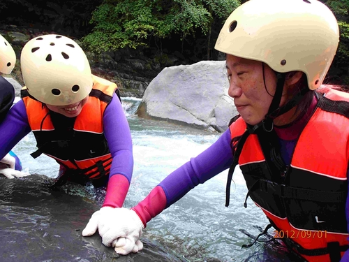 志工拉著視障者的手去碰觸石塊，同時也感受湍急的水流。