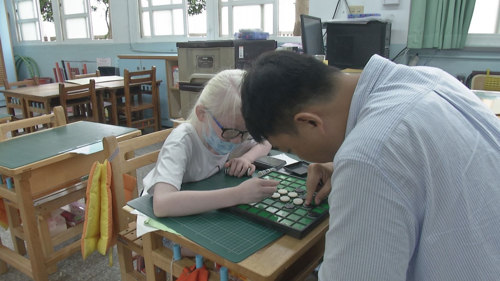 李文煥老師有教無類，圖為與白化症學生下棋。